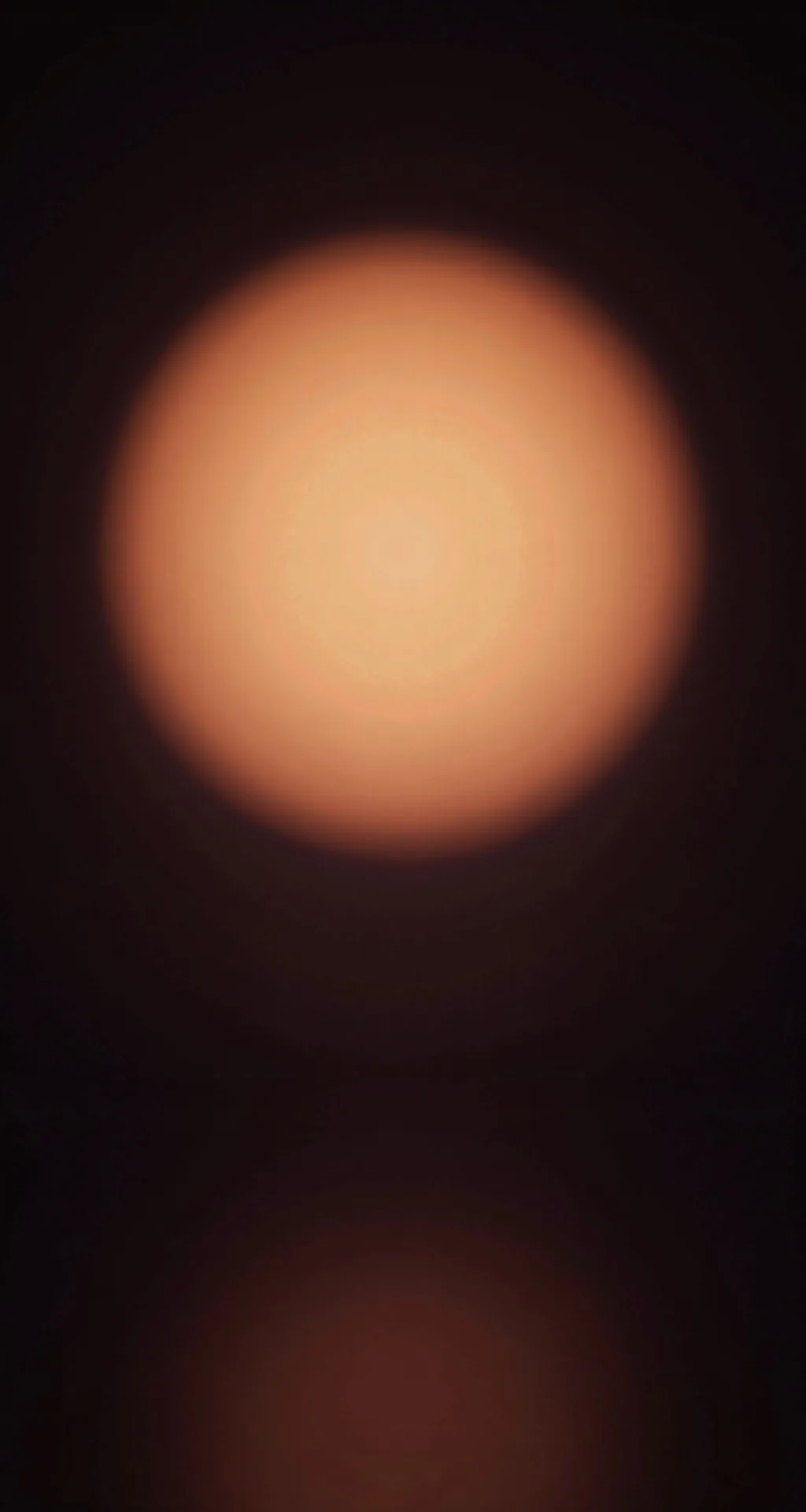 A soft amber halo of light on a dark wall.