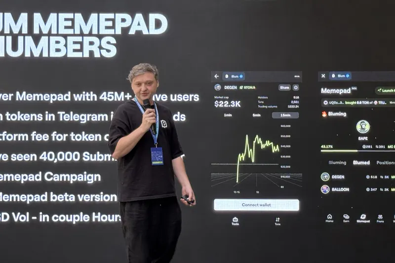 Igor on stage in a Blum T-shirt, presenting a slide titled Blum Memepad in numbers, with two Memepad screens beside him.