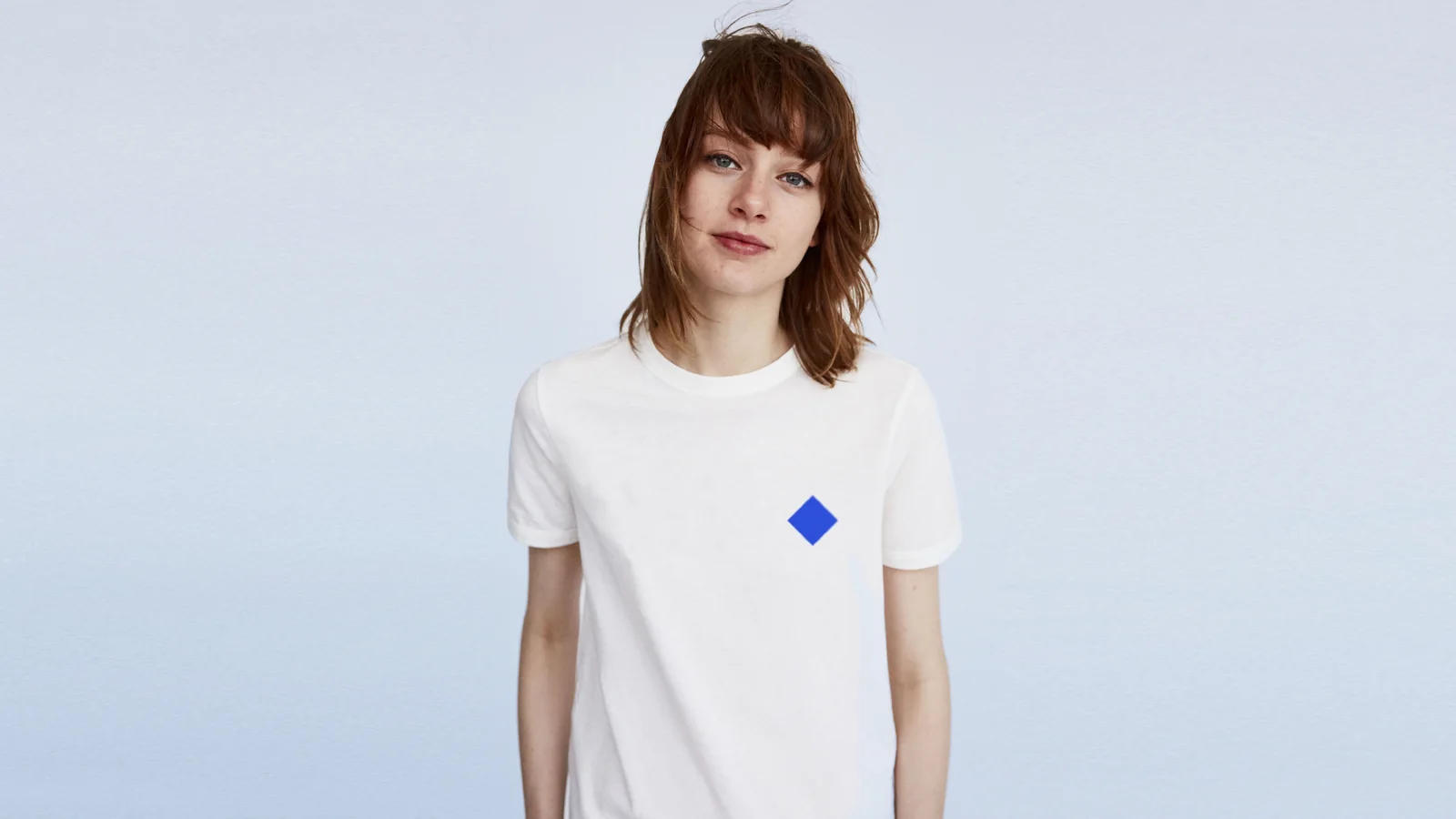 A woman in a white T-shirt with a single blue diamond on the chest.